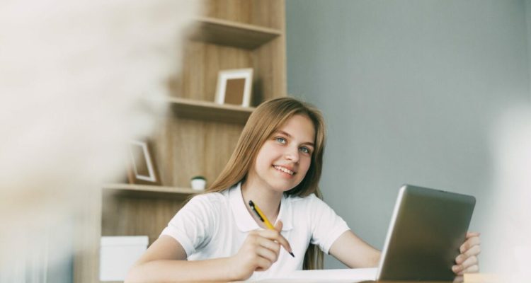 A cute girl is studying at home with a digital tablet, thinking about her homework