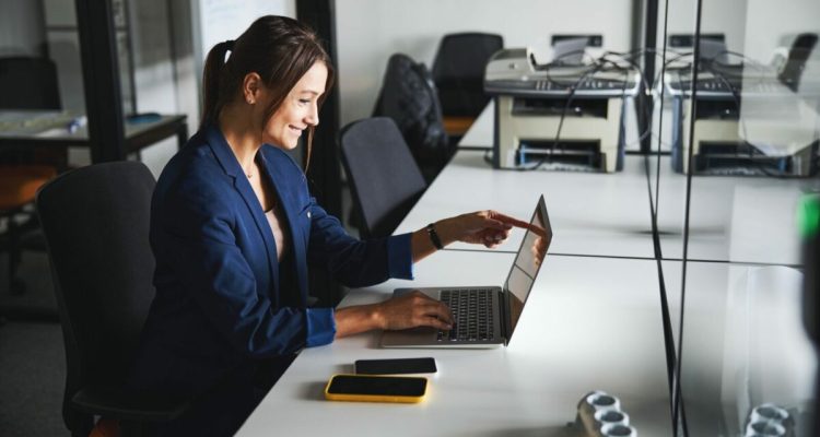 Beautiful elegant web designer working at the laptop while using internet in the workspace