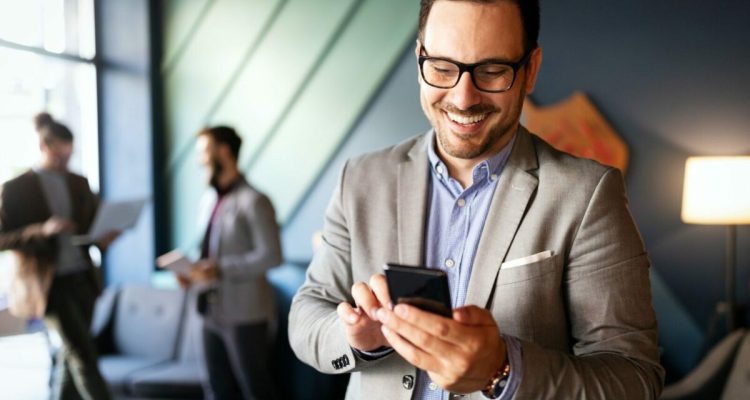 Handsome businessman checking emails on the phone in modern office