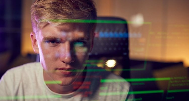 Male Teenage Hacker With Data Reflected From Computer Screen